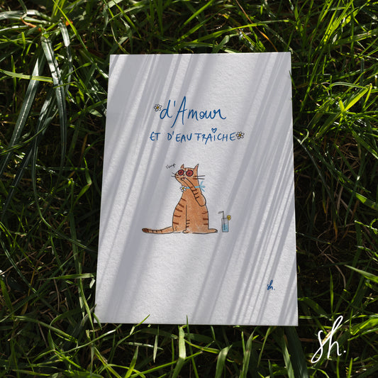carte postale posée dans l'herbe sous un joli soleil qui reflète l'ombre de l'herbe dessus, un chat fait sa toilette devant son cocktail et il est écrit d'amour est d'eau fraîche 